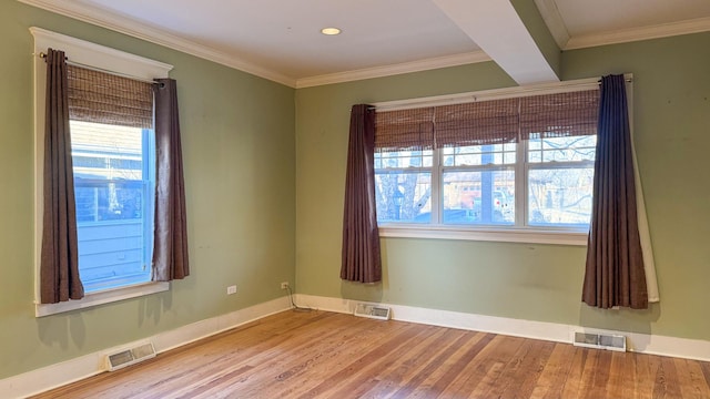 unfurnished room featuring visible vents, ornamental molding, and wood finished floors