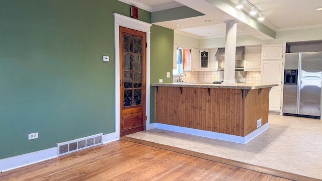 kitchen with visible vents, stainless steel fridge, a kitchen bar, and ornamental molding