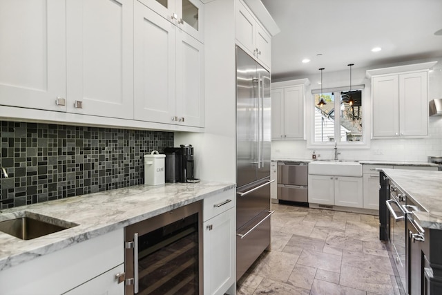 kitchen with a sink, beverage cooler, white cabinetry, and stainless steel appliances