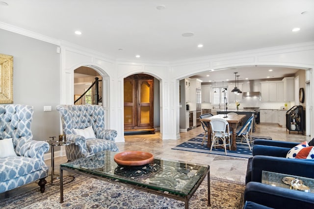 living room featuring stairs, crown molding, recessed lighting, and arched walkways