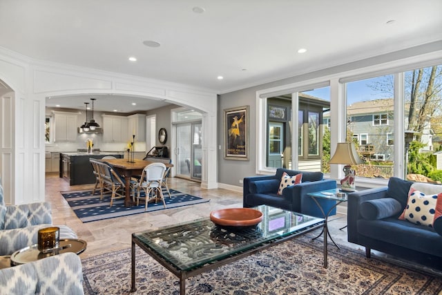 living room featuring recessed lighting, baseboards, arched walkways, and crown molding