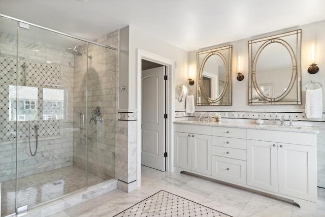 full bath featuring double vanity, marble finish floor, a stall shower, and a sink