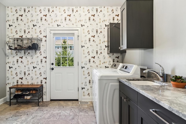 laundry room featuring baseboards, wallpapered walls, separate washer and dryer, cabinet space, and a sink