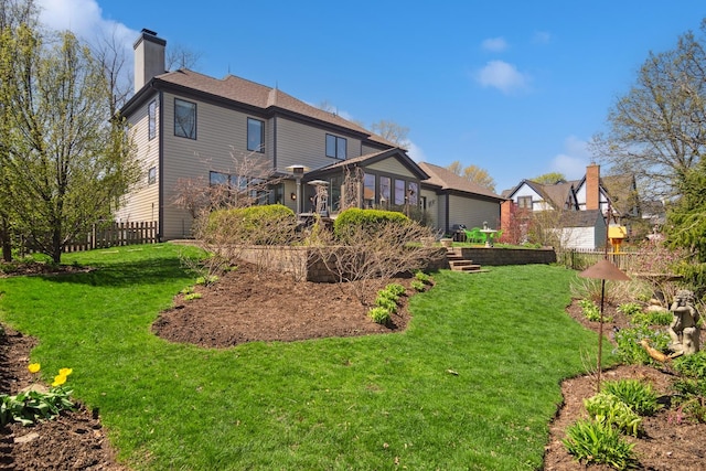 back of house featuring a lawn, a chimney, and fence