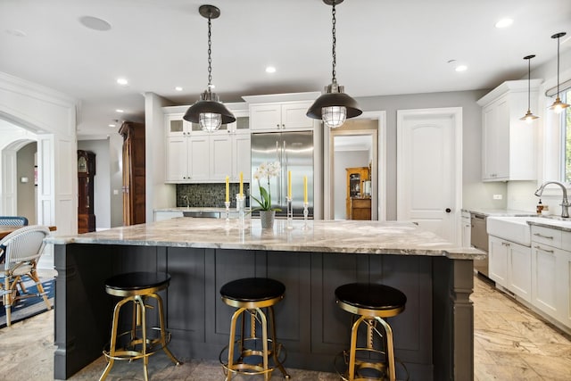 kitchen featuring stainless steel built in fridge, a large island, a sink, white cabinetry, and decorative backsplash