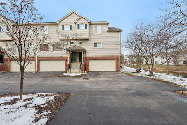 multi unit property featuring driveway, brick siding, and a garage