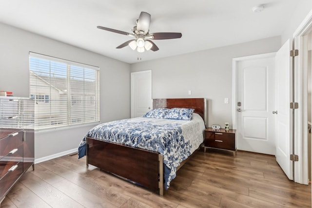 bedroom featuring baseboards, wood finished floors, and a ceiling fan