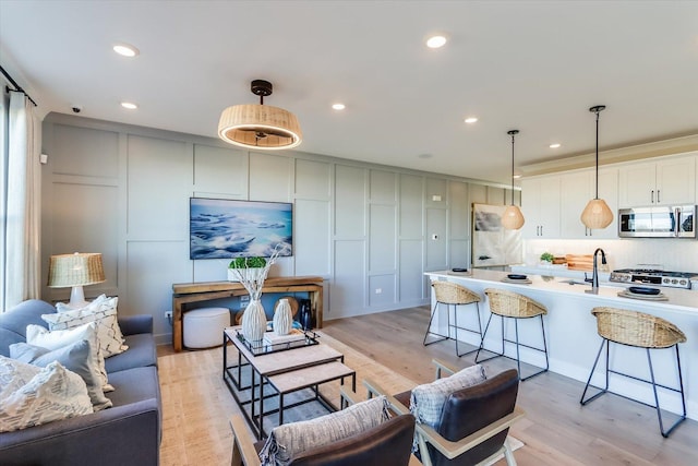 living area featuring recessed lighting, a decorative wall, and light wood-style flooring