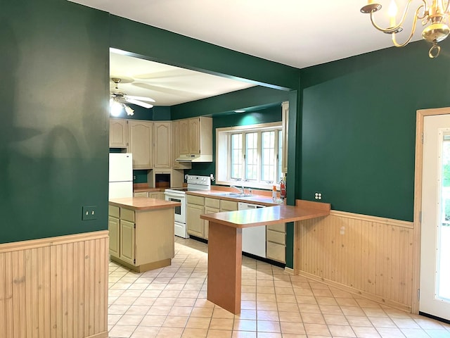 kitchen with white appliances, a ceiling fan, light countertops, wainscoting, and a center island