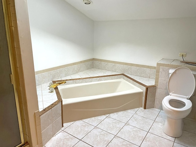 full bath with tile patterned floors, a garden tub, toilet, tile walls, and wainscoting