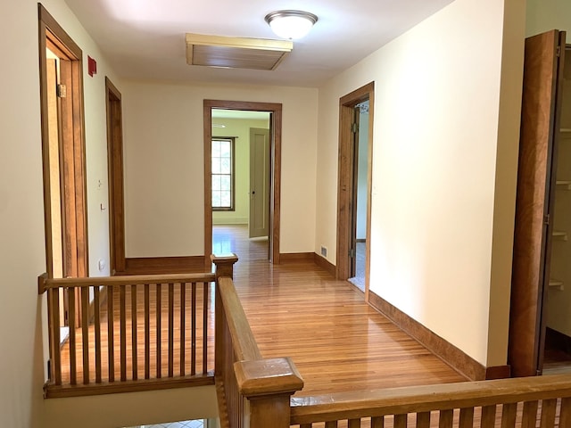 hallway featuring light wood finished floors, an upstairs landing, and baseboards