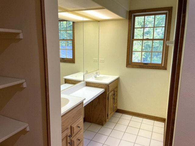 bathroom featuring tile patterned floors, baseboards, two vanities, and a sink