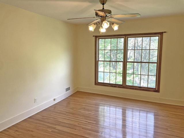 unfurnished room featuring ceiling fan, visible vents, baseboards, and wood finished floors