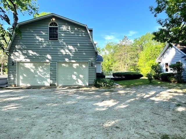 view of side of home featuring a gambrel roof and a garage