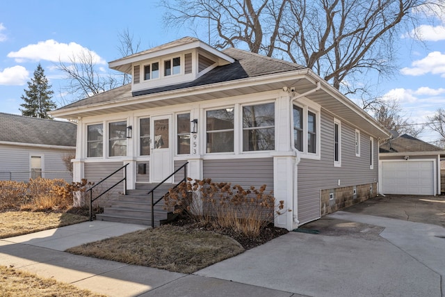 bungalow-style house featuring concrete driveway, a detached garage, and an outdoor structure