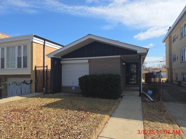 view of front of house featuring fence, an attached garage, brick siding, and board and batten siding