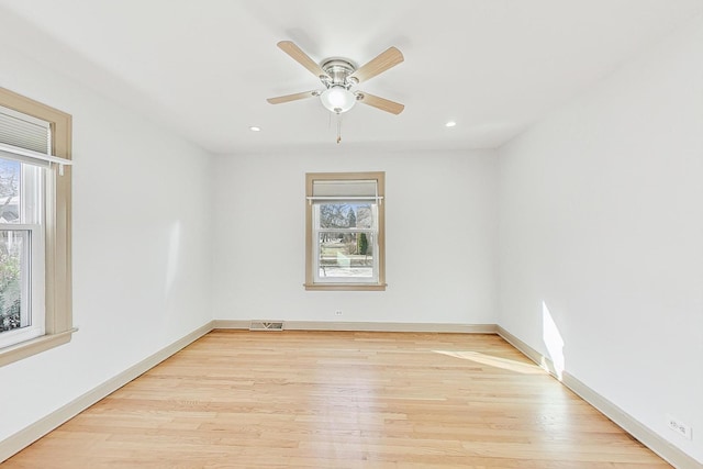 empty room featuring visible vents, light wood-style flooring, a ceiling fan, and baseboards