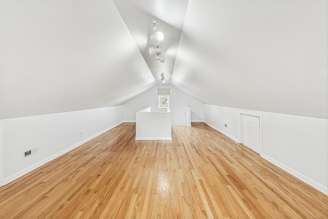 bonus room featuring visible vents, baseboards, lofted ceiling, and light wood-style floors