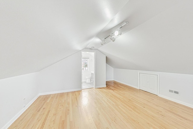 bonus room with lofted ceiling, wood finished floors, baseboards, and visible vents