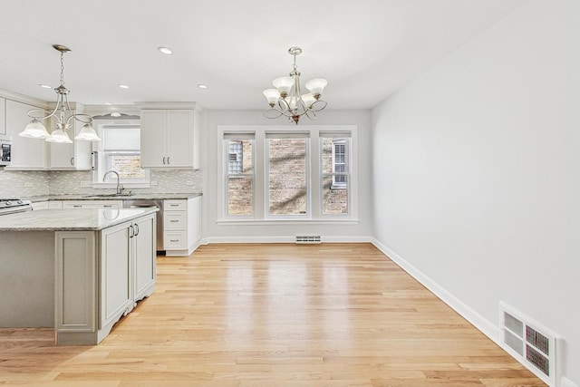 kitchen with decorative backsplash, an inviting chandelier, visible vents, and white cabinetry