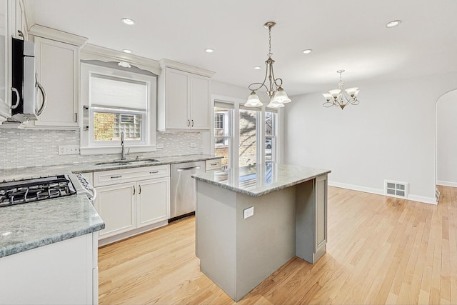 kitchen featuring visible vents, decorative backsplash, light wood-style floors, stainless steel appliances, and a sink