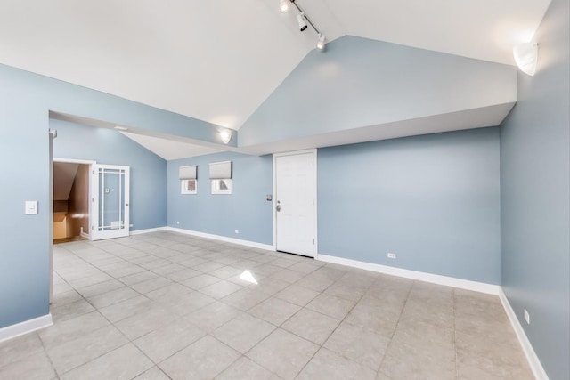 tiled empty room with rail lighting, high vaulted ceiling, and baseboards