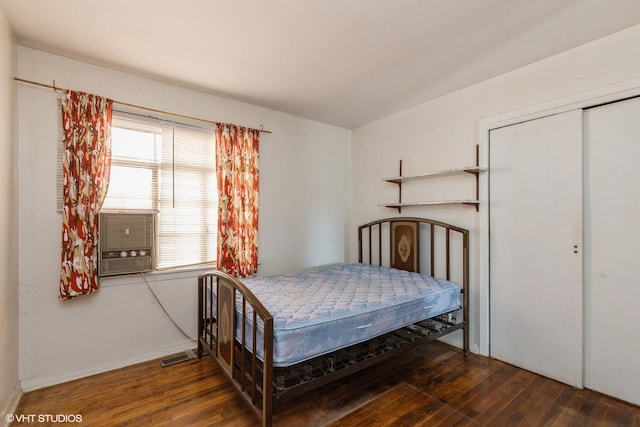 bedroom with hardwood / wood-style floors, cooling unit, visible vents, and a closet