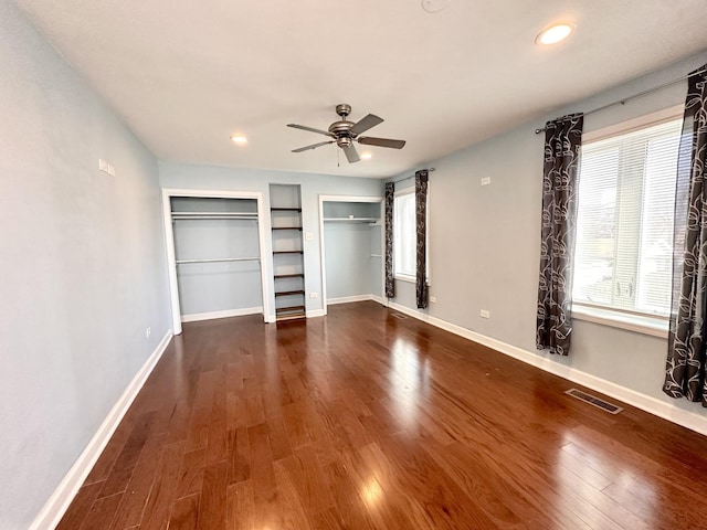 unfurnished bedroom with ceiling fan, wood finished floors, visible vents, and baseboards