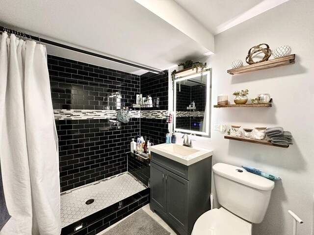 full bath featuring vanity, toilet, and a tile shower