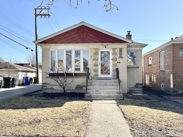 bungalow with entry steps, brick siding, and a chimney