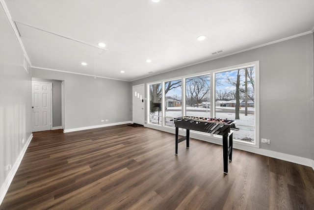 recreation room featuring visible vents, attic access, crown molding, and dark wood-style flooring