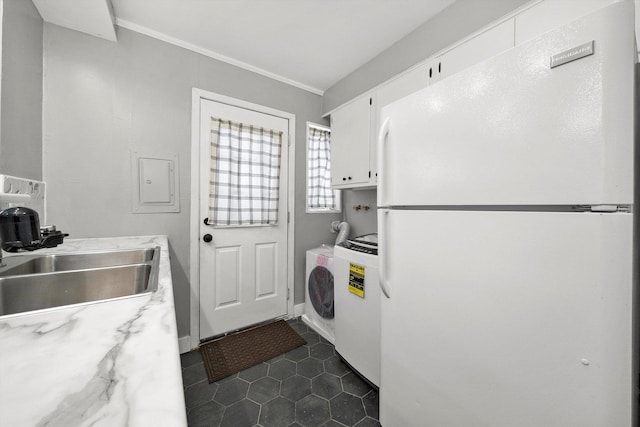 kitchen featuring white cabinetry, light countertops, freestanding refrigerator, washer / clothes dryer, and a sink