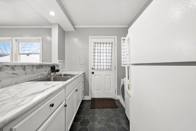 kitchen featuring dark tile patterned floors, a sink, white cabinetry, freestanding refrigerator, and crown molding