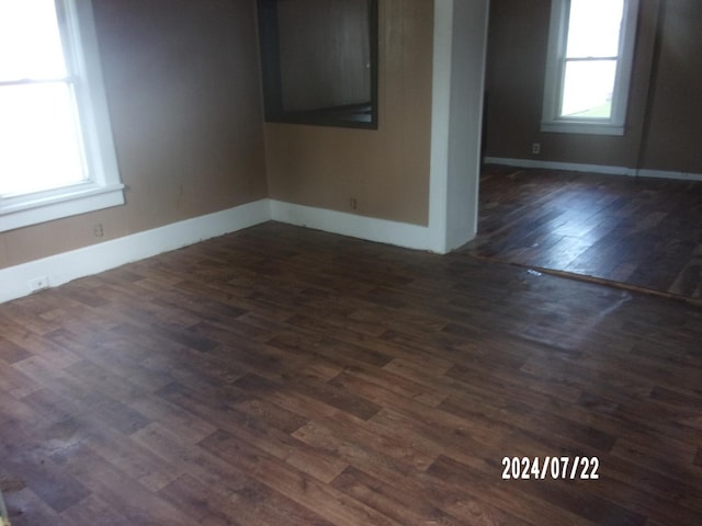 spare room with dark wood-type flooring and baseboards