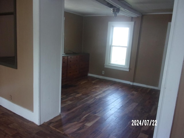 unfurnished room with crown molding, baseboards, and dark wood-style flooring