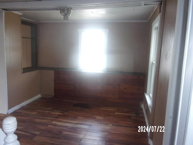 empty room with wood finished floors, baseboards, and ornamental molding