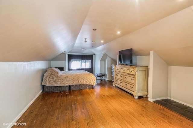 bedroom featuring hardwood / wood-style floors, vaulted ceiling, and baseboards