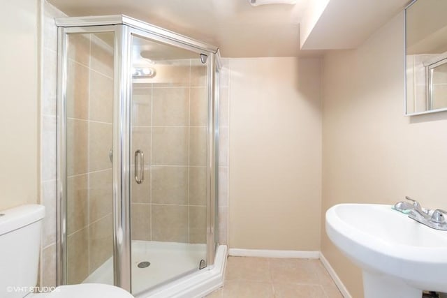 bathroom featuring baseboards, a sink, tile patterned flooring, a shower stall, and toilet