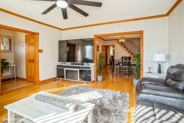 living area featuring ornamental molding, baseboards, and wood finished floors