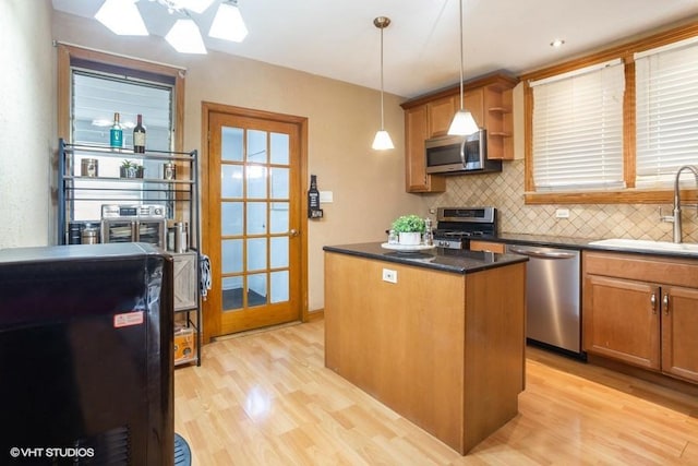 kitchen with tasteful backsplash, a kitchen island, light wood-style floors, stainless steel appliances, and a sink