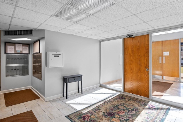 interior space with tile patterned flooring, visible vents, baseboards, mail area, and a paneled ceiling