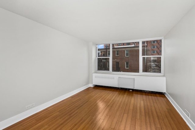 spare room featuring baseboards and wood finished floors