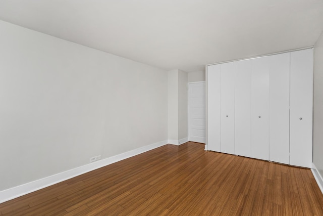 unfurnished bedroom with a closet, baseboards, and wood finished floors