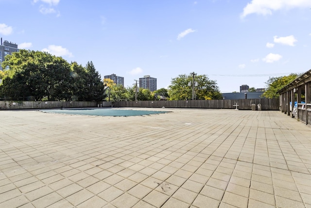 community pool with a patio area and fence