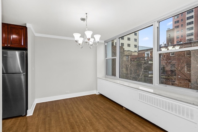 unfurnished dining area featuring a chandelier, baseboards, dark wood-style floors, and ornamental molding