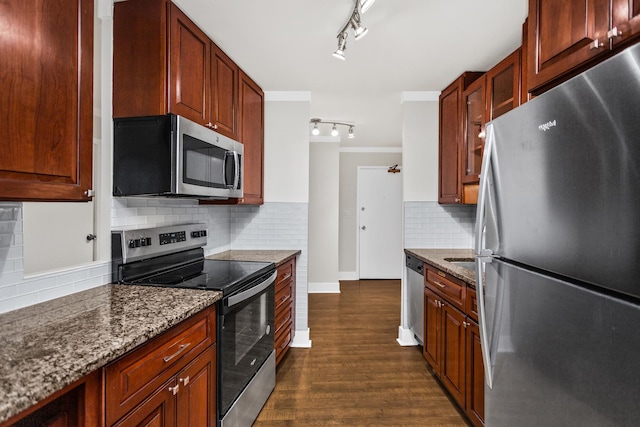 kitchen featuring dark wood-style floors, dark stone counters, stainless steel appliances, crown molding, and backsplash