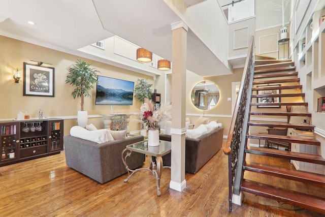 living room with stairway, visible vents, wood finished floors, and crown molding