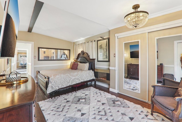 bedroom with crown molding, baseboards, lofted ceiling, wood finished floors, and a notable chandelier