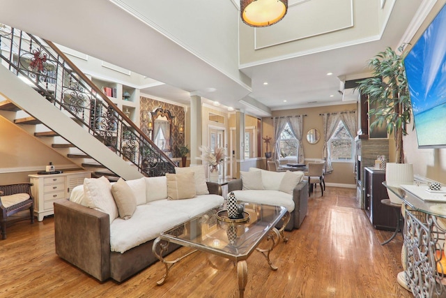 living room featuring stairway, baseboards, wood finished floors, and ornamental molding