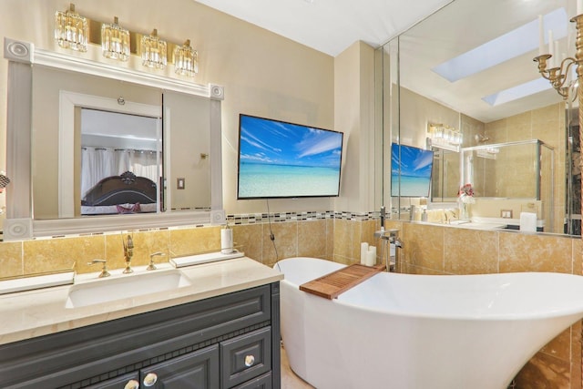 full bath featuring tile walls, a skylight, a shower stall, a freestanding bath, and vanity